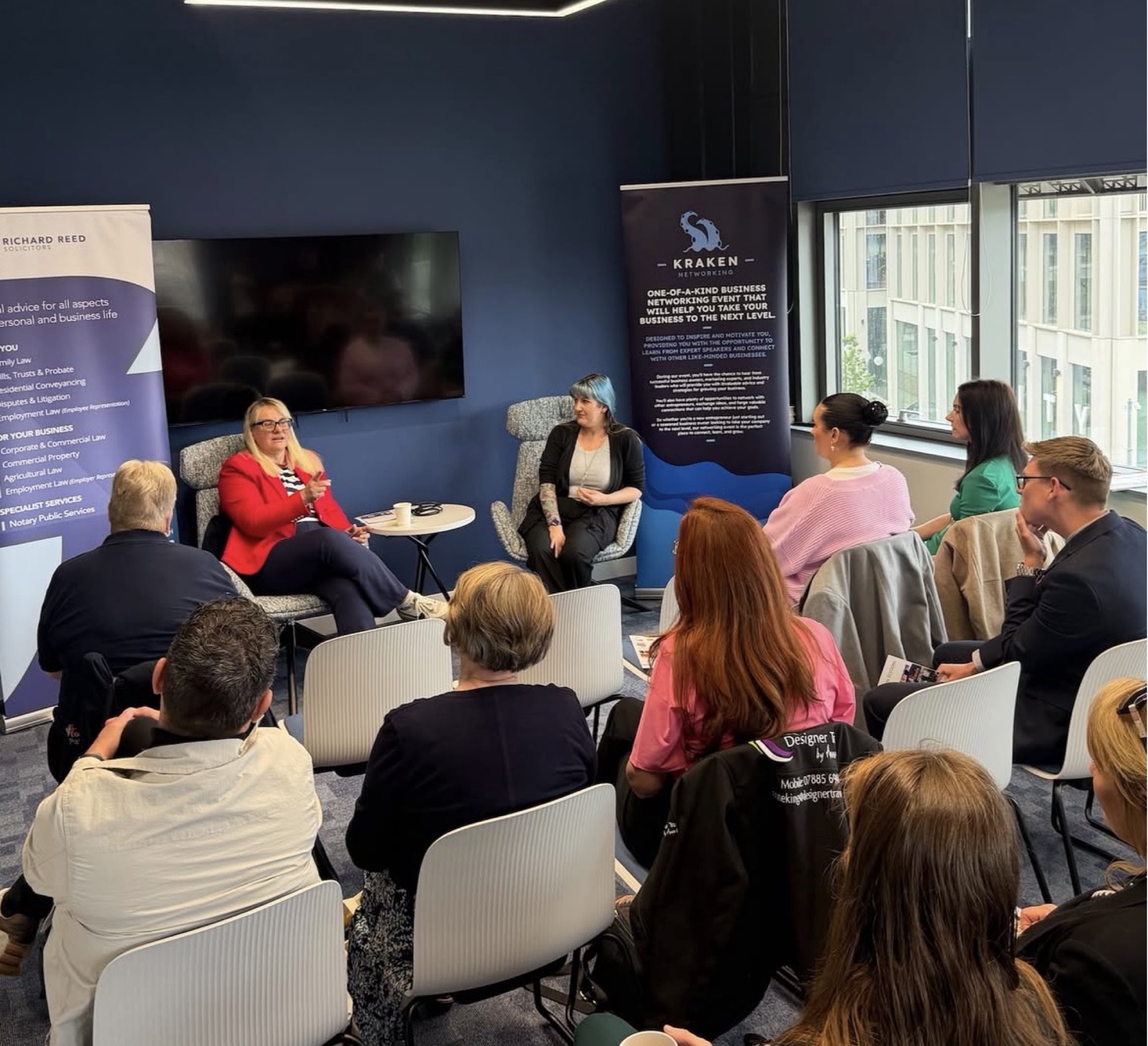 Club members at a business networking event, seated in a circle listening to two speakers